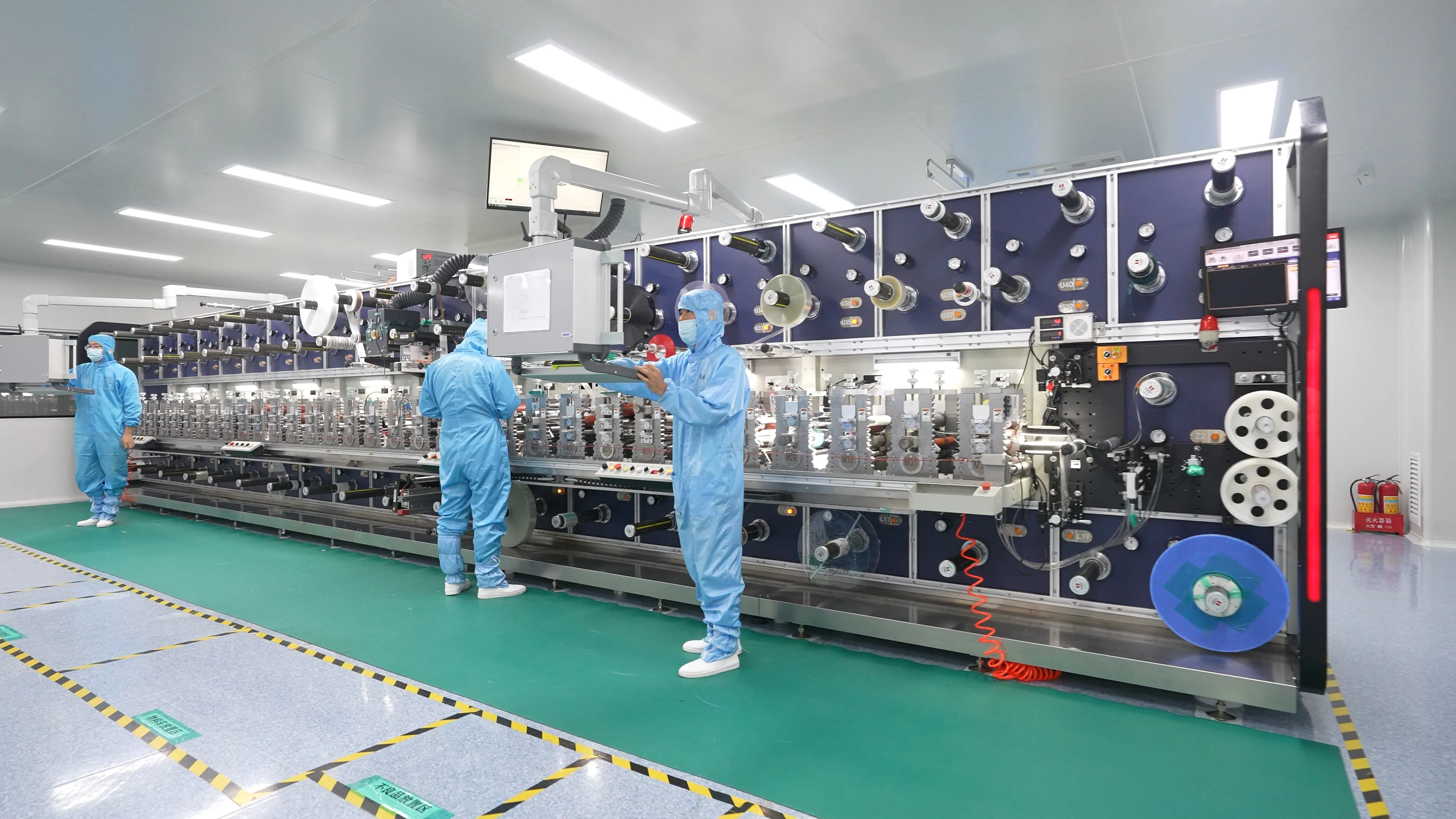 Engineers operating automated medical adhesive converting equipment